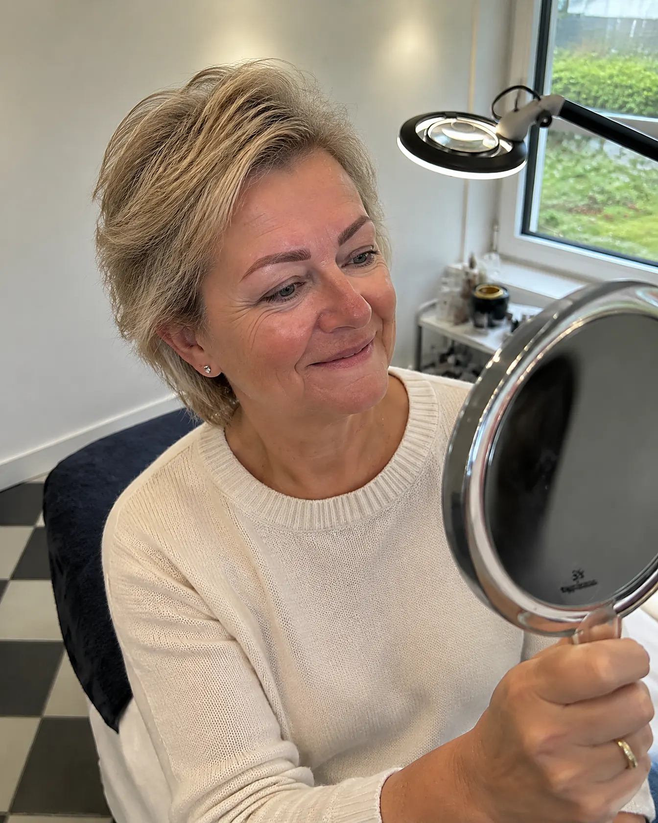 Klant bekijkt haar vollere wenkbrauwen in een handspiegel in de salon